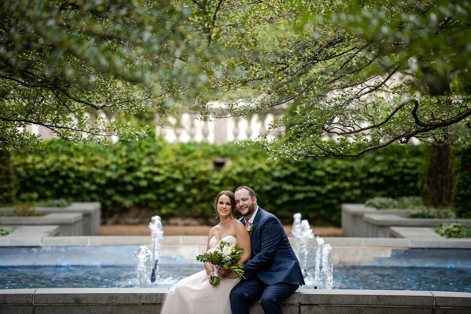 Bride and groom in garden with fountain