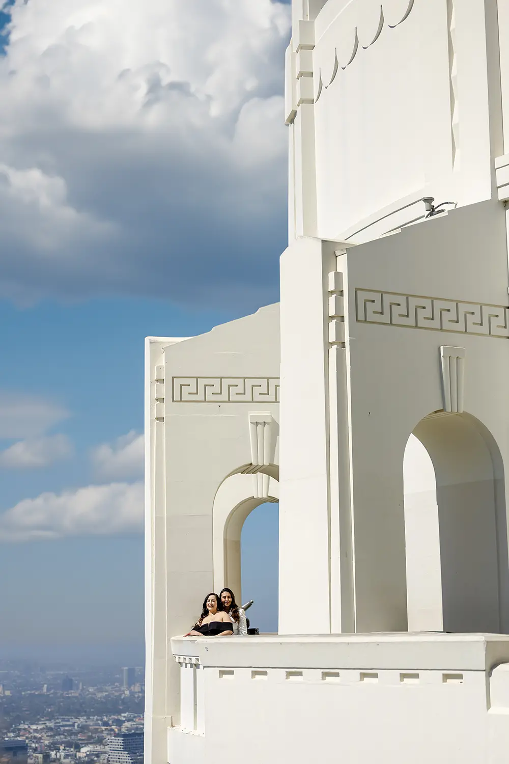 LGBT couple posing at the Griffith Park Observatory Landmark with cityscape of Los Angeles